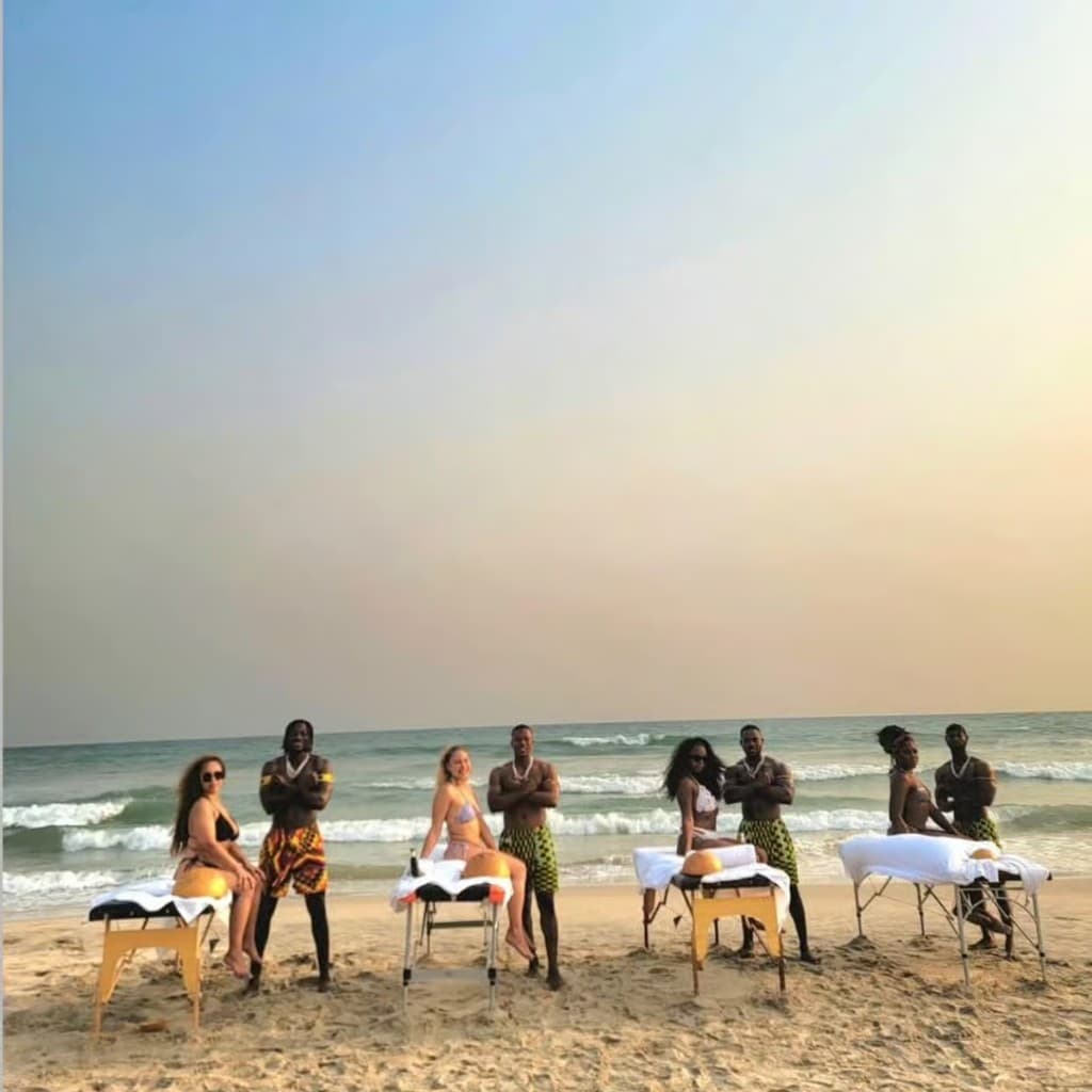 Beach massage setup with ocean and staff in traditional dress